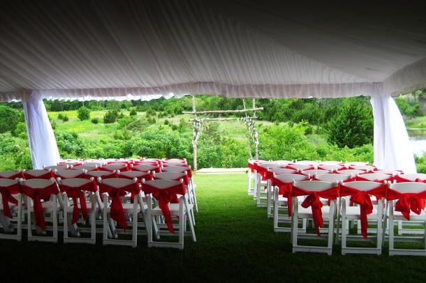 A beautiful day for an outdoor wedding Chairs set with red sashes tied 
