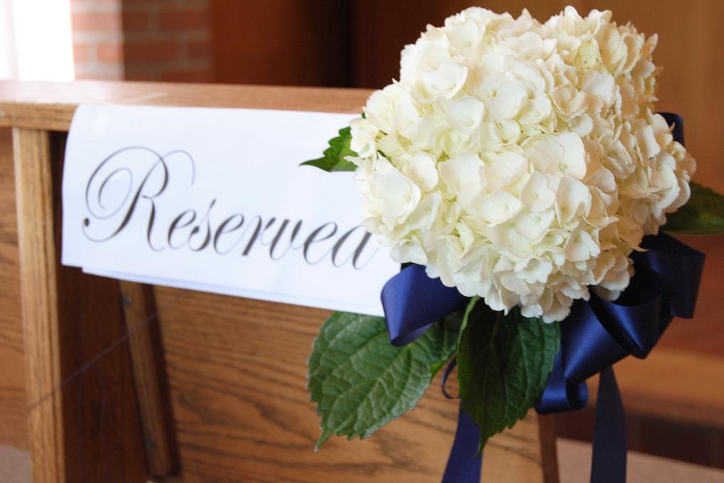 Pew accented with white hydrangeas with navy blue streamers